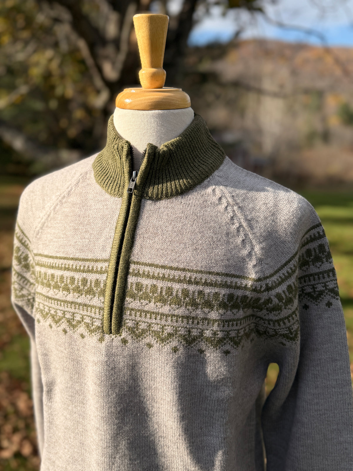 grey quarter zip mock neck sweater with olive pattern across chest and biceps. Mock neck is also olive. Mannequin is against tree background.