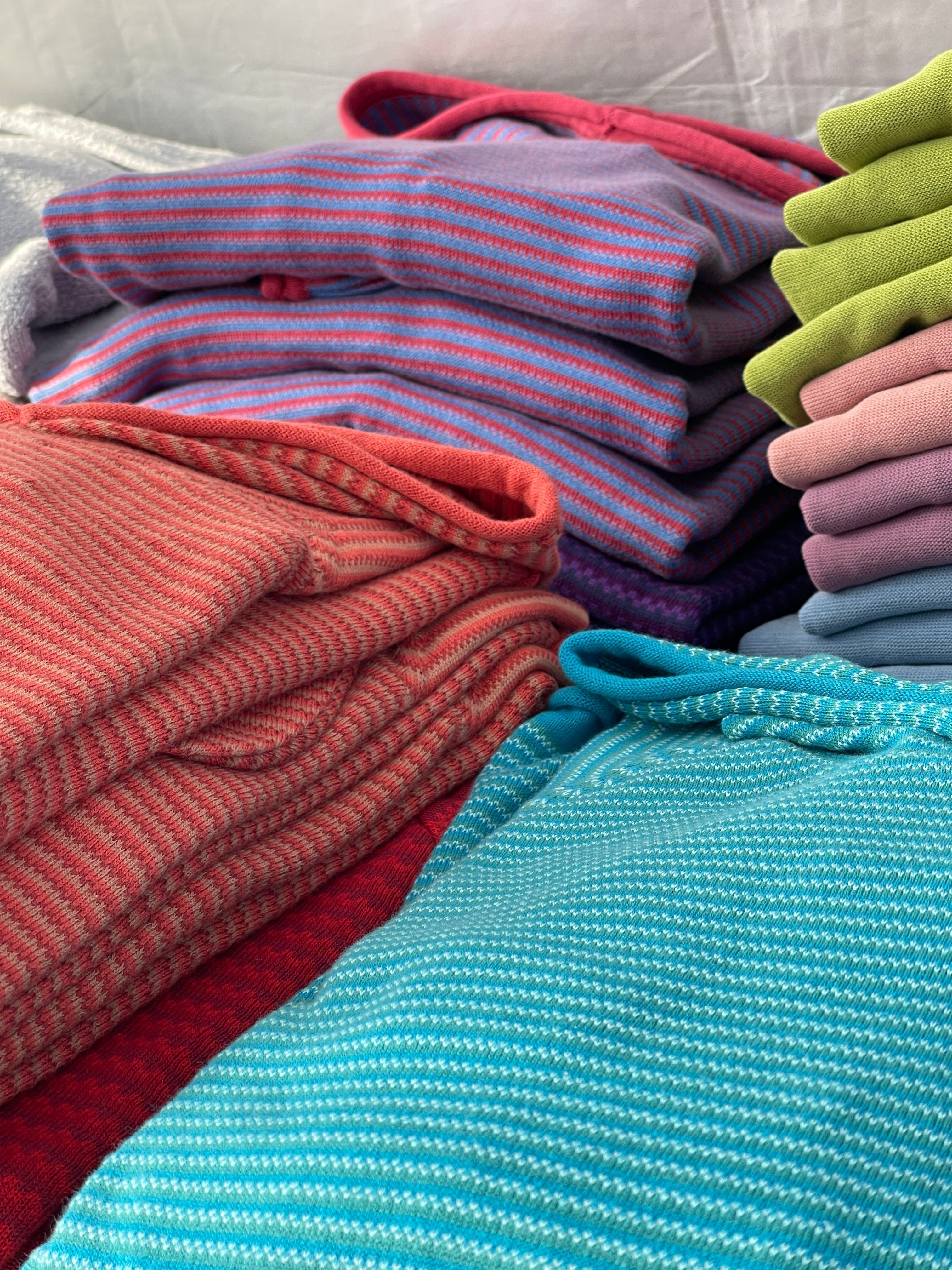 Purple, Red, Turquoise, and Lime sweaters folded in stacks