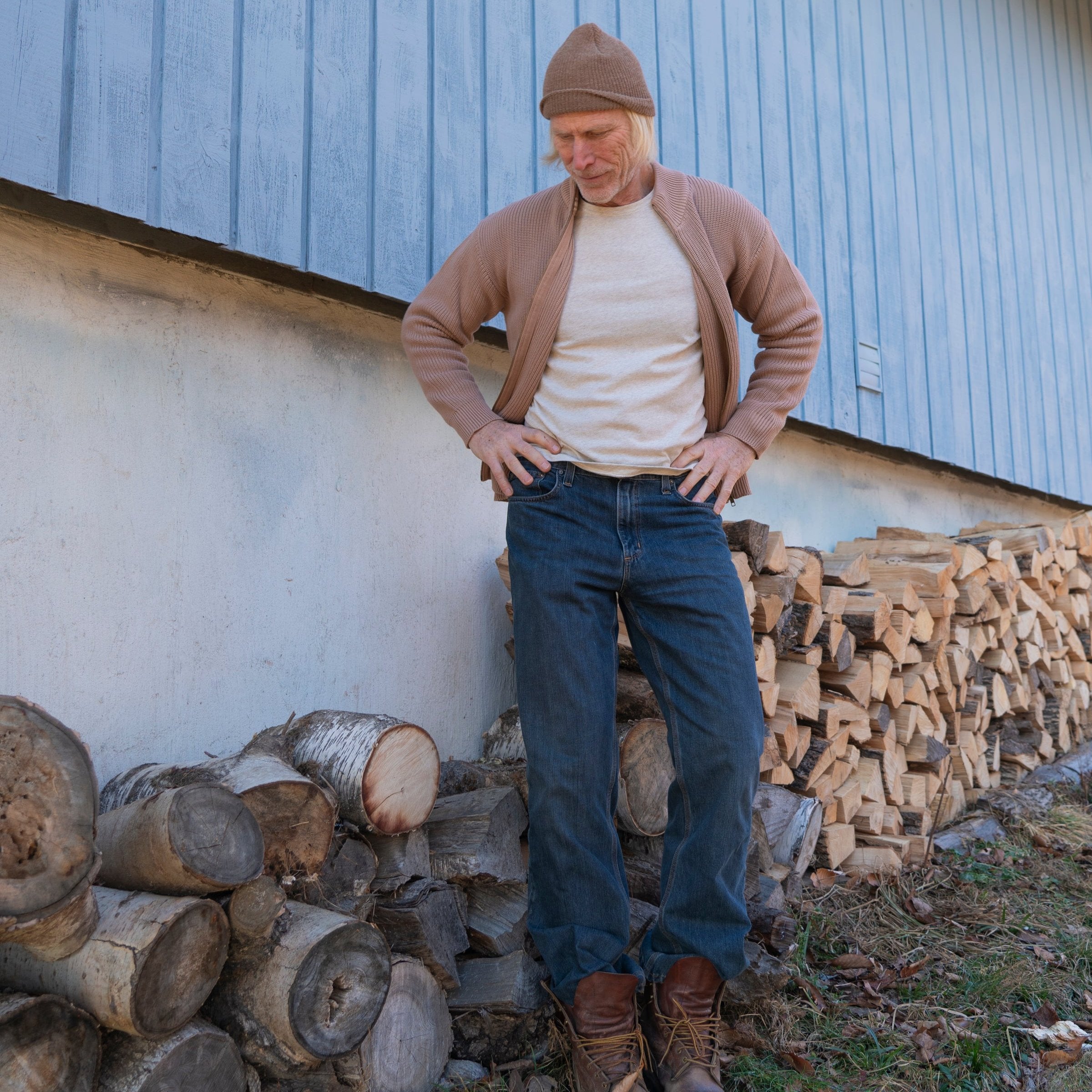 Man in black front zip cardigan sweater with blue pants in front of a wooden star 