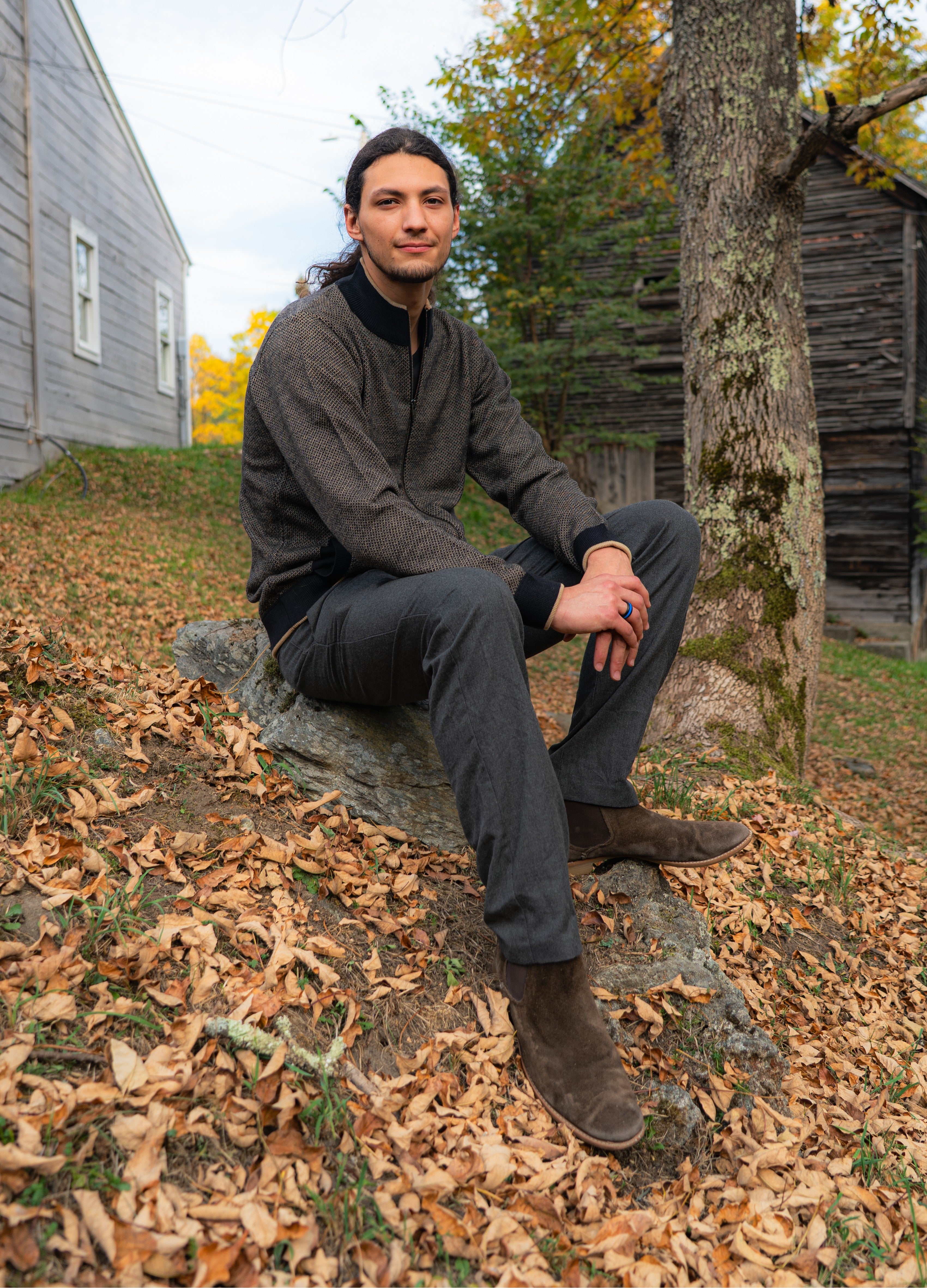 Man in black front zip cardigan sweater with blue pants in front of a wooden star 